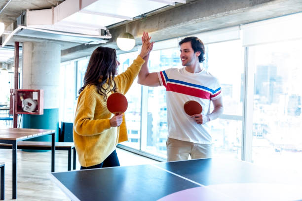 Colleagues high-fiving at the table tennis match Man and woman celebrating a point, while play table tennis during a break at the office table tennis stock pictures, royalty-free photos & images