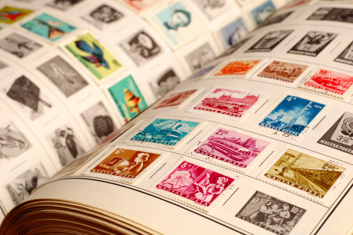 Closeup color photo of a vintage stamp album with colorful old stamps.  Selective focus on front stamps.