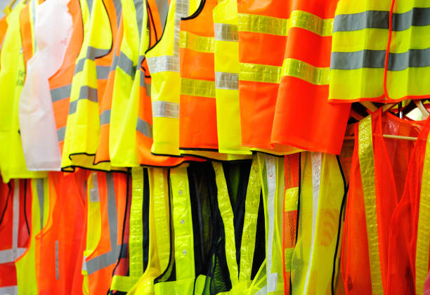 Collection of security reflective vests. Collection of security reflective cloths, orange and yellow, hanging in row vests. waistcoat stock pictures, royalty-free photos & images