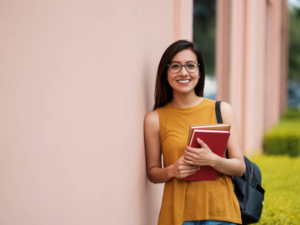 College girl with books smiling at the camera Front View, Young Woman, Student, Books,Happy, Campus, Millennial, medium shot stock pictures, royalty-free photos & images