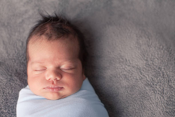 Color Image of Peaceful Newborn Sleeping, Wrapped in Blanket stock photo