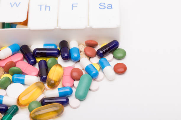 Color pills and capsules next to pill organizer stock photo