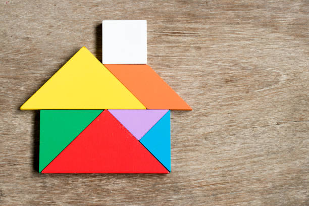 rompecabezas de tangram de color en forma de casa sobre fondo de madera - tangram casa fotografías e imágenes de stock