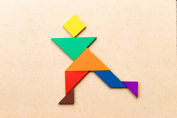 Color tangram puzzle in running man shape on wood background Color tangram puzzle in running man shape on wood background asien startblock stock pictures, royalty-free photos & images