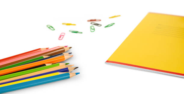 colored pencils, notebook and paper clips on a white background. isolated stationery - kleurpotloden accident stockfoto's en -beelden