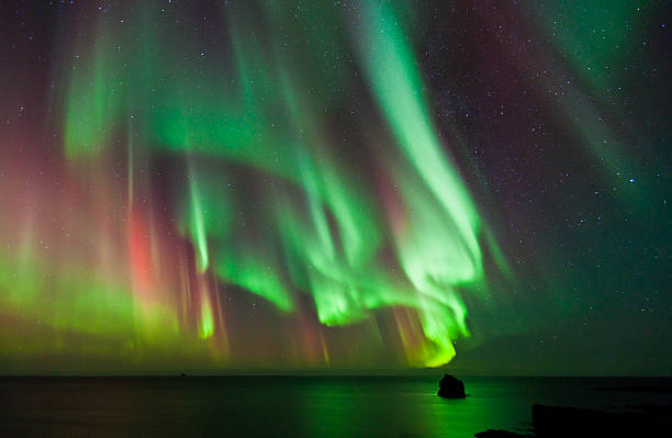 Colorful Aurora Borealis, Iceland Strong multi colored Aurora Borealis over the Atlantic Ocean. geomagnetic storm stock pictures, royalty-free photos & images