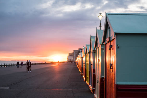 coloridas cabañas de playa durante la puesta de sol en brighton y hove, inglaterra - brighton fotografías e imágenes de stock