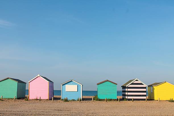 Colorful beach huts on the seafront Colorful row of beach huts on the beach beach hut stock pictures, royalty-free photos & images