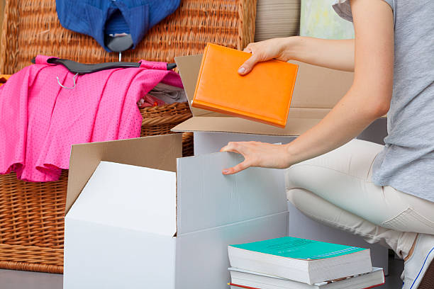 Colorful books packing A woman packing colorful books into a cradboard box arrangement stock pictures, royalty-free photos & images