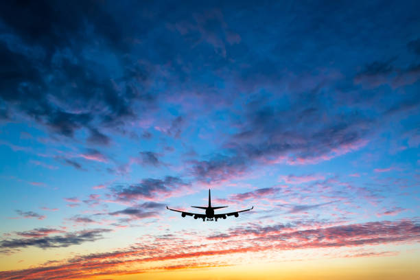 Colorful bright sunset with flying airplane silhouette stock photo