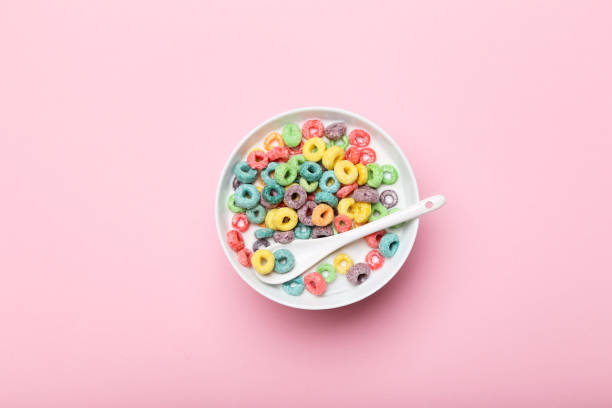 Colorful corn rings in bowl with milk and spoon on pink background stock photo