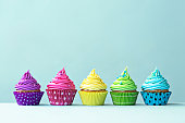 Row of colorful cupcakes on blue