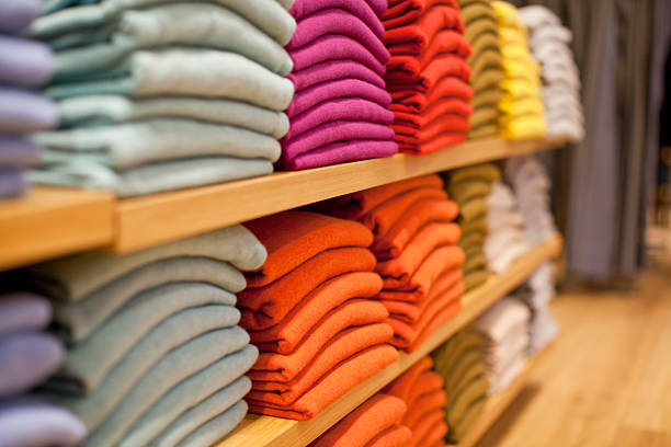 Colorful display of sweaters on shelf in store stock photo