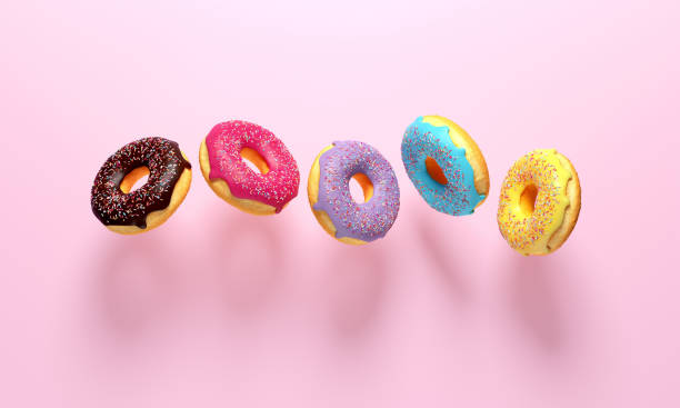 Colorful donuts flying on pink background. stock photo