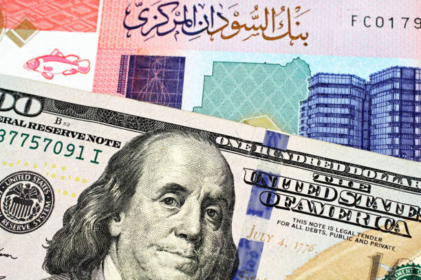 A colorful fifty Sudanese pound bank note with an American one hundred dollar bill stock photo