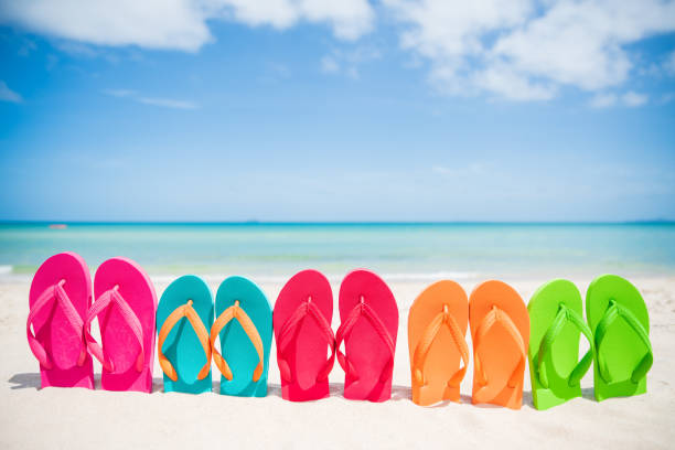 colorful flip flop on sandy beach, green sea and blue sky background for summer holiday and vacation concept. colorful flip flop on sandy beach, green sea and blue sky background for summer holiday and vacation concept. flip flop stock pictures, royalty-free photos & images