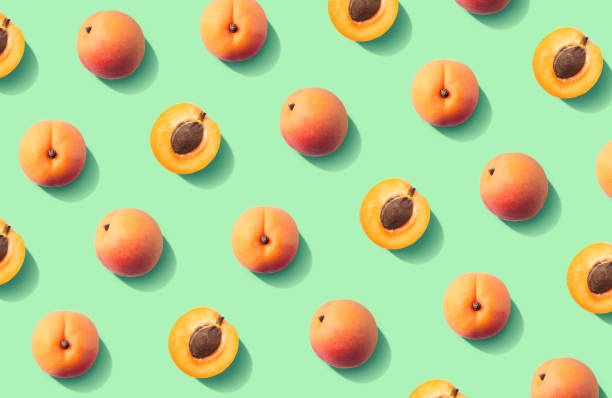 Colorful fruit pattern of fresh apricots Colorful fruit pattern of fresh apricots on green pastel background, top view, flat lay apricot stock pictures, royalty-free photos & images