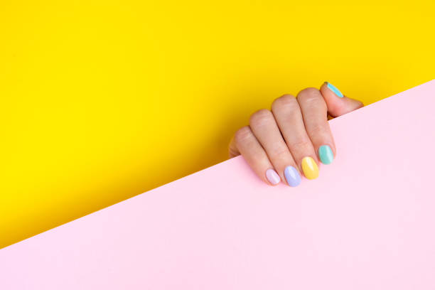 Colorful gel manicure on yellow and pastel pink background. stock photo