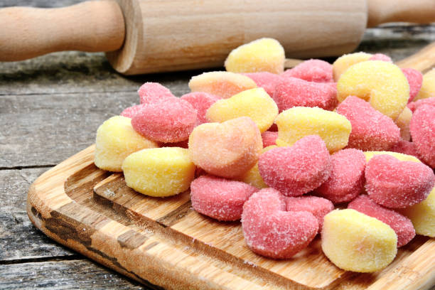 Colorful gnocchi hearts on a old table with rolling pin stock photo