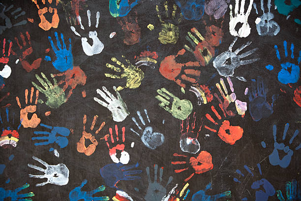 colorful handprints "colorful children's handprints on a textured black wall - fragment of a busstop wall in Bali, Indonesia" handprint stock pictures, royalty-free photos & images