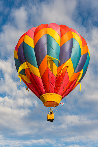 A colorful hot air balloon flying in a blue sky.