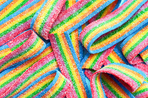 Colorful jelly candies in sugar sprinkles. Sour flavored rainbow candy background. Top view