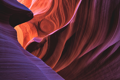 Orange, blue and purple light reflects off the Navajo Sandstone in Lower Antelope Canyon, Arizona. Lower Antelope Canyon lies in the Navajo Nation Indian Reservation in the Southwest, USA. This slot canyon was formed over time as water from flash floods carved a slot canyon through the rock.