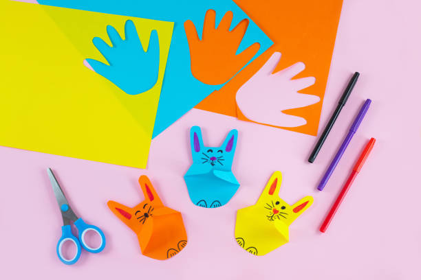 Colorful paper bunnies from childrens palm of their hand. stock photo