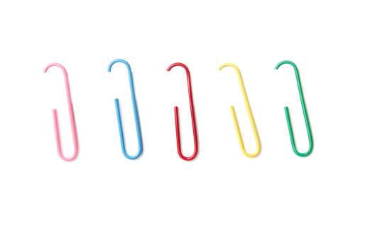 Set of colorful paper clips at the paper sheet isolated on white background