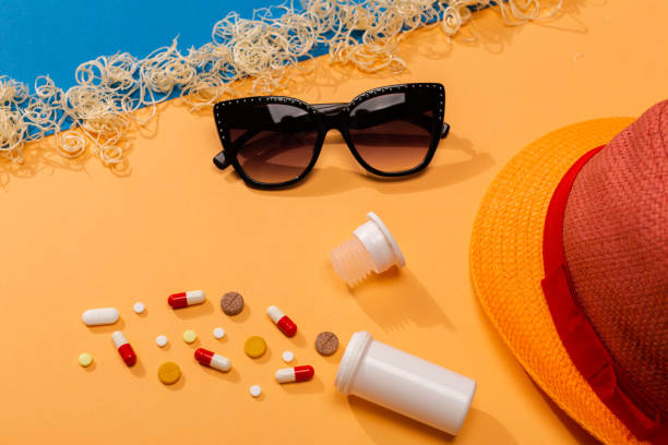 Colorful pills on orange background with sunglasses and hat. stock photo