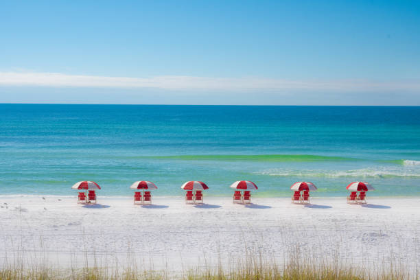 Colorful Row of Red Chairs on the Beach A row of chairs and umbrellas on a white sand beach. florida beaches stock pictures, royalty-free photos & images