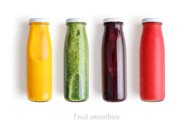 Colorful smoothies in glass Colorful smoothies in glass bottles isolated on white background, top view. orange smoothie stock pictures, royalty-free photos & images