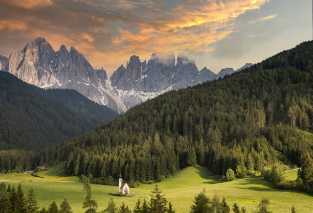 Colorful sunset in the mountains with a small chapel. Dolomite in Italy stock photo