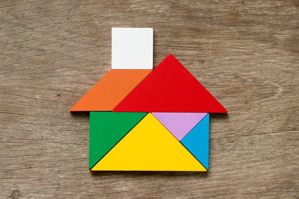 rompecabezas de tangram colores en forma de página sobre fondo de madera - tangram casa fotografías e imágenes de stock