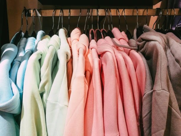 Colorful t-shirts and hoodies hanging in a row in the clothing store stock photo