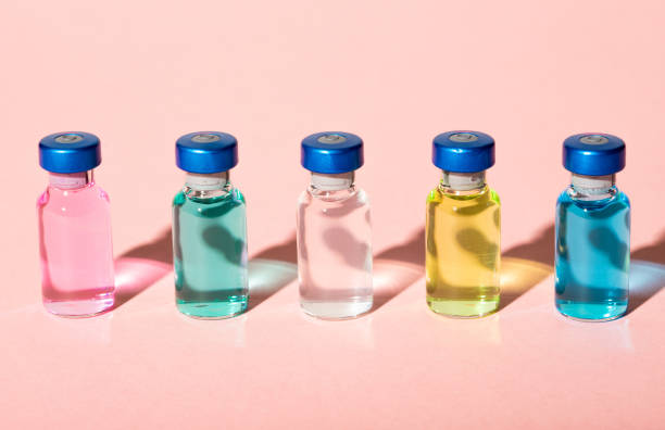 Colorful vaccine or medicine vials on pink background with trendy hard shadows on pink background stock photo