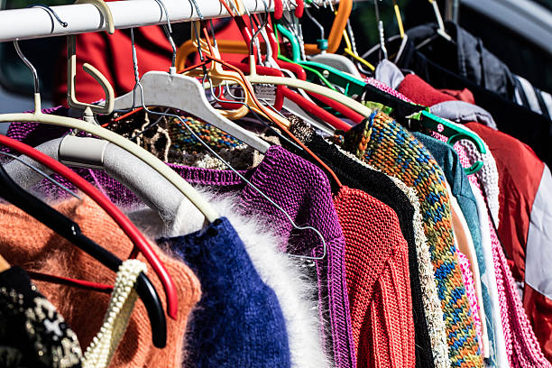 colorful women's sweaters for second life at flea market rack of fast fashion colorful women's sweaters on display for reselling,recycling,donation,reusing or welfare for second life sold at flea market, outdoors thrift store stock pictures, royalty-free photos & images