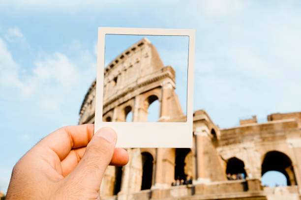 Colosseum in Rome, Italy closeup of a young man with a white frame in his hand, framing the famous Flavian Amphitheatre or Colosseum, in Rome, Italy, simulating an instant photograph souvenir stock pictures, royalty-free photos & images