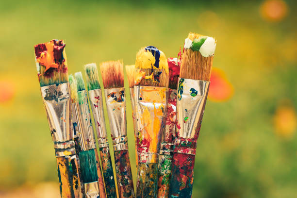 colourful paintbrushes on green background - schilderen stockfoto's en -beelden