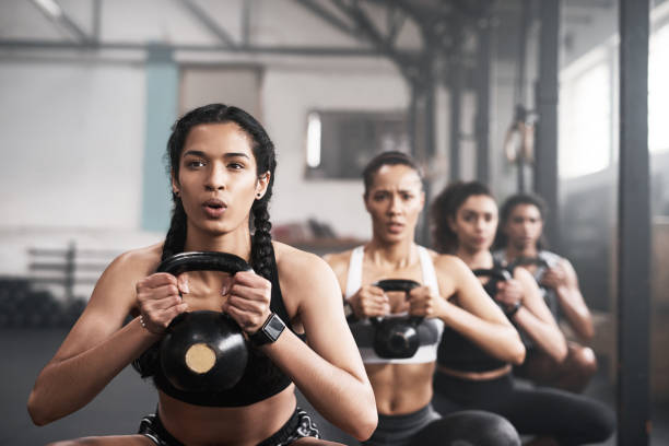 Shot of a group of fit young women working out with kettle bells at the gym