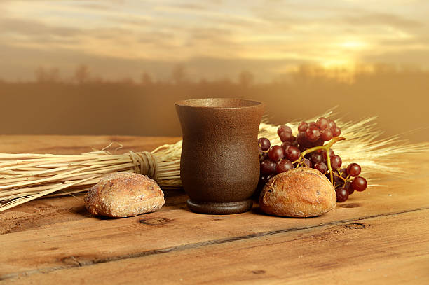 Communion Elements at Sunset Cup of wine, bread. grapes and wheat on vintage table with warm sunset in background chalice photos stock pictures, royalty-free photos & images