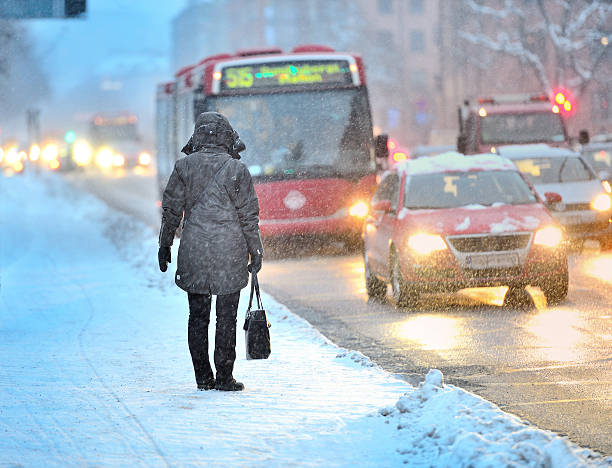 Commuters waiting for arriving bus in snowstorm stock photo
