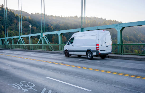 Compact business cargo mini van running on arched St John bridge White popular compact comfortable commercial useful economical small business or cargo delivery mini van running on the St Johns bridge with truss and ropes on divided road to point of destination mini van stock pictures, royalty-free photos & images