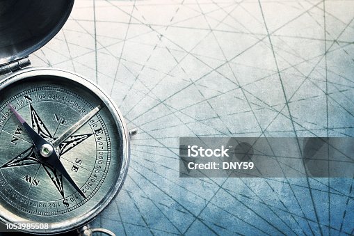 istock Compass On Old World Map With Navigational Lines On Textured Surface 1053985508