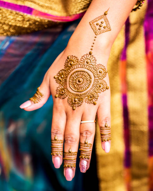 Completed Mehndi design displayed on hand and fingers of Indian wedding guest. stock photo
