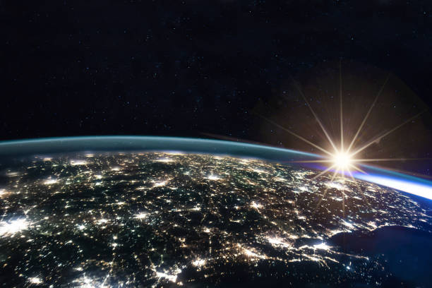 Composite image of the sun rising on earth view from space with the lights of the cities illuminated at night. Human activities, greenhouse gas emissions concept. Elements of this image are furnished by NASA stock photo