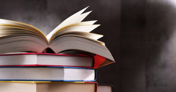 A composition with an open book lying on a stack of other books stock photo