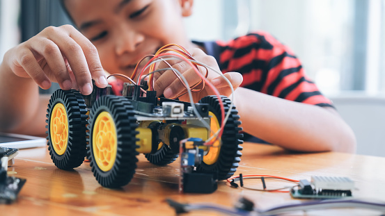 Working on Handmade car model, construction on electronic. Concentrated boy creating robot at lab. Early development, diy, innovation, modern technology concept.