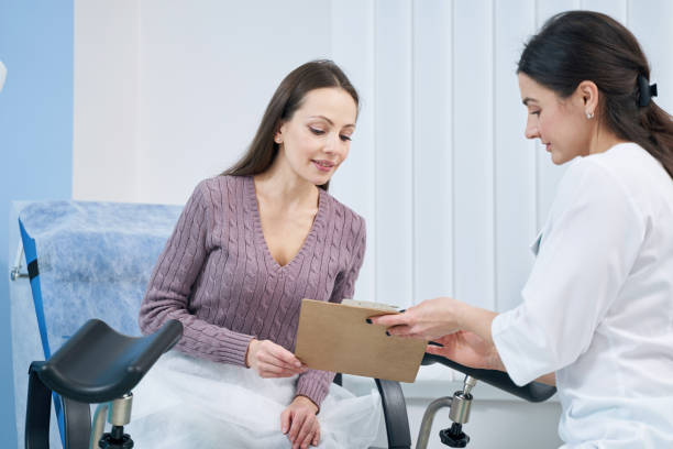 Concentrated woman reading document in presence of her doctor stock photo