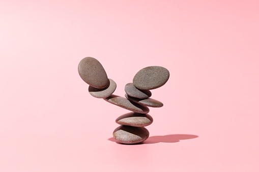 Concept of balance of gray stones on a pink background